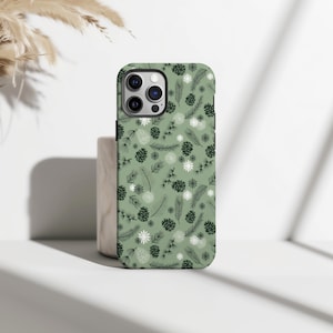 May include: A sage green phone case featuring a repeating pattern of pine cones, pine needles, and snowflakes. The case has a glossy finish and a camera cutout. The design is a winter or holiday theme.