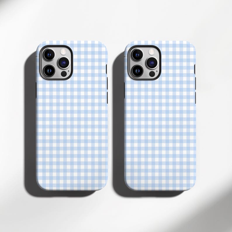 May include: Two phone cases with a light blue and white gingham pattern. The cases have a camera cutout and a black border. The cases are on a white background with a shadow.