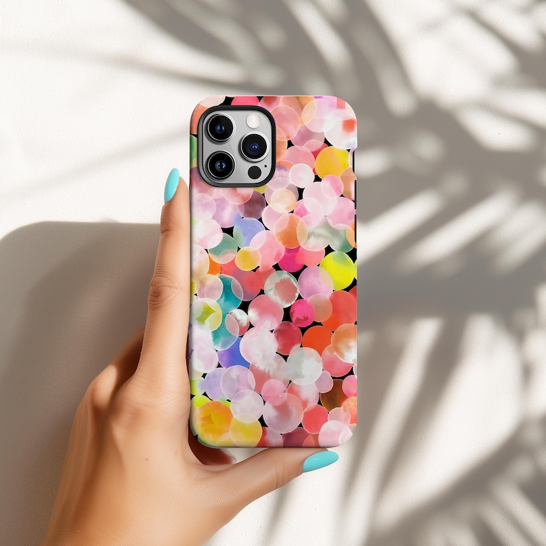 May include: A colorful phone case featuring a pattern of overlapping watercolor circles in shades of pink, orange, yellow, and blue against a black background. The case has a glossy finish and a camera cutout.