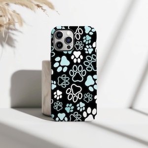 May include: Black phone case featuring a pattern of white and pale blue paw prints. The case has a glossy finish and a camera cutout. The design is a playful and modern take on a pet-themed accessory, suitable for animal lovers.