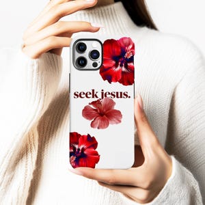 May include: White phone case featuring red hibiscus flowers and the text "seek jesus." The case has a glossy finish and a camera cutout. The design includes three hibiscus flowers in varying sizes and shades of red.