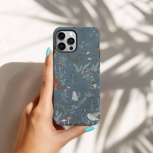 Könnte beinhalten: Dunkelblaue Handyhülle mit einem Waldmuster, das Eichhörnchen, Füchse und Pilze zeigt. Die Hülle hat eine matte Oberfläche und ist für ein Smartphone konzipiert.