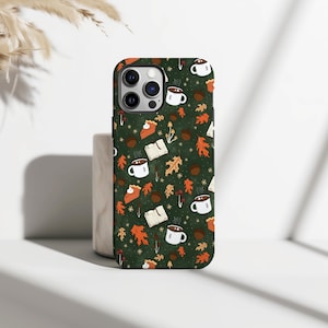 May include: A phone case with a dark green background featuring a repeating pattern of autumn-themed illustrations. The design includes white mugs of coffee, open books, orange leaves, mushrooms, and pie slices.