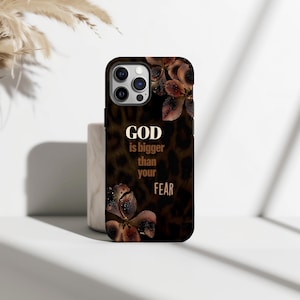 May include: A black phone case with a leopard print design and brown floral accents. The case features the text "GOD is bigger than your FEAR" in a gold color.