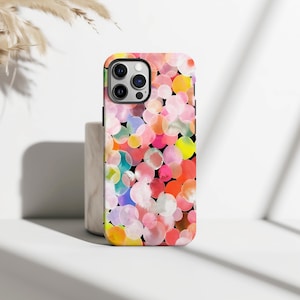 May include: A colorful phone case featuring a pattern of overlapping watercolor circles in shades of pink, yellow, orange, and blue against a black background. The case has a black camera module and a glossy finish.