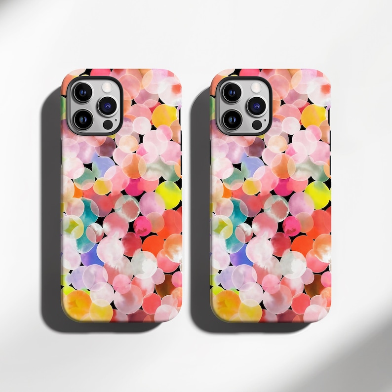 May include: Two phone cases with a colorful, abstract design. The cases feature a pattern of overlapping circles in shades of pink, orange, yellow, blue, and green against a black background. The cases have a glossy finish and are designed for a smartphone.