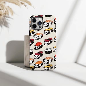 Puede incluir: Funda de teléfono con un patrón repetido de rollos de sushi con caras de panda. El sushi incluye salmón, atún y huevas. La funda es de color blanquecino y tiene un recorte para la cámara.