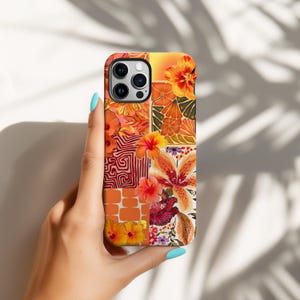 May include: A vibrant phone case with a patchwork design of orange and yellow floral patterns. The case has a square camera cutout and is held by a hand. The design includes various flower illustrations in a square pattern.