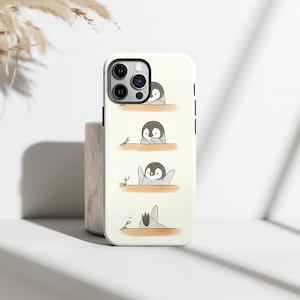 Peut inclure: Coque de téléphone blanche avec une illustration de pingouins en noir et blanc avec des accents orange, interagissant avec de petits insectes verts. Le design présente des pingouins dans différentes poses. Le boîtier a un bord noir et une découpe pour l'appareil photo.