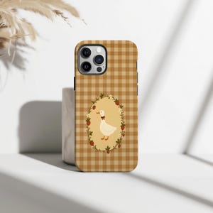 May include: A smartphone case with a brown and beige gingham pattern. The case has an oval design with a white goose wearing a red bow tie, surrounded by strawberries and leaves. The case is designed for a mobile phone.