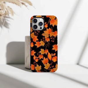 May include: A black phone case featuring a vibrant autumn leaf design. The case is covered with orange, yellow, and brown leaves, creating a seasonal aesthetic. The leaves are set against a black background.
