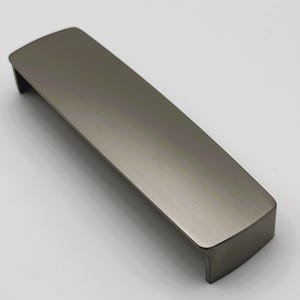 Peut inclure: Une poignée de meuble rectangulaire de couleur canon de fusil avec un dessus incurvé et une finition en métal brossé. Ce matériel a un design minimaliste et convient aux tiroirs ou aux armoires.