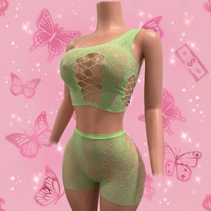 May include: A green one-piece lingerie set with a mesh design. The top is a one-shoulder crop top with a cut-out design. The bottom is a pair of shorts with a cut-out design on the side.