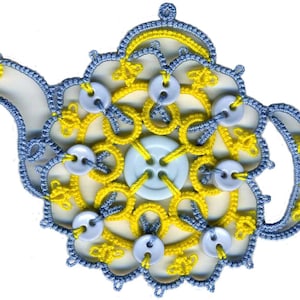 Puede incluir: Una tetera de ganchillo azul y amarilla con botones blancos. La tetera es una pieza de arte decorativa hecha a mano.