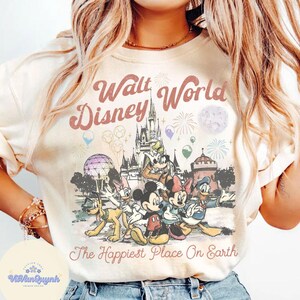 K&ouml;nnte beinhalten: Cremefarbenes Sweatshirt mit einer Disney-Grafik, die Micky Maus, Minnie Maus und Donald Duck vor dem Cinderella-Schloss zeigt. Der Text "Walt World Disney" und "The Happiest Place On Earth" ist auf der Vorderseite aufgedruckt.