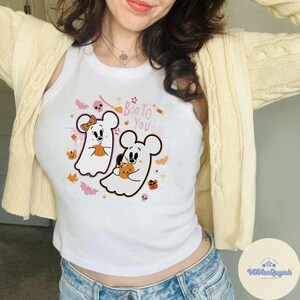 May include: White tank top with a Halloween-themed graphic. The design features two cartoon ghost mice holding pumpkins, with the text "Boo To You" in pink and orange. Bats, stars, and pumpkins complete the festive design.