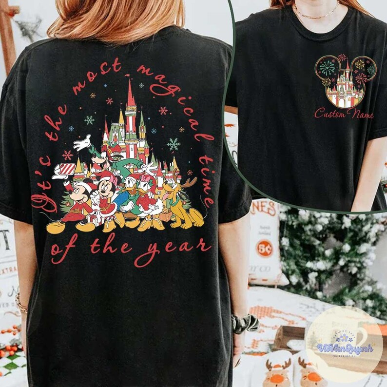 Puede incluir: Camiseta negra con un dise&ntilde;o festivo de Disney, que incluye personajes, un castillo y el texto "It's the most magical time of the year." Tambi&eacute;n se ve un dise&ntilde;o m&aacute;s peque&ntilde;o con un castillo y fuegos artificiales.