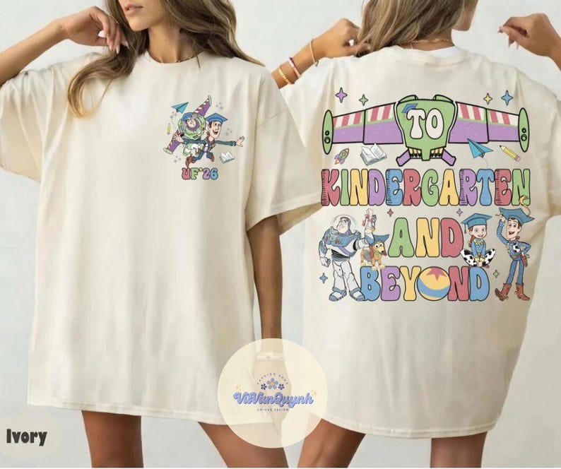 May include: Ivory-colored t-shirt featuring a colorful graphic of Buzz Lightyear and Woody from Toy Story, with the text "UF '26" on the front. The back of the shirt displays the phrase "TO KINDERGARTEN AND BEYOND" with additional Toy Story characters.