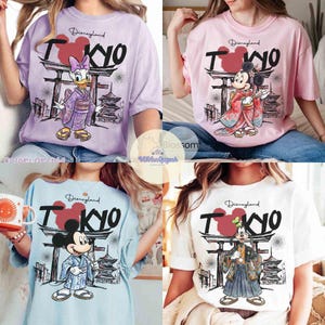 K&ouml;nnte beinhalten: Vier T-Shirts in Pastellfarben, jedes mit einem anderen Disney-Charakter in traditioneller japanischer Kleidung. Die Shirts zeigen den Text "Disneyland Tokyo" mit einem roten Mickey Mouse-Kopf, der das "O" in Tokyo ersetzt. Zu den Charakteren geh&ouml;ren Daisy Duck, Mickey Mouse und Goofy.