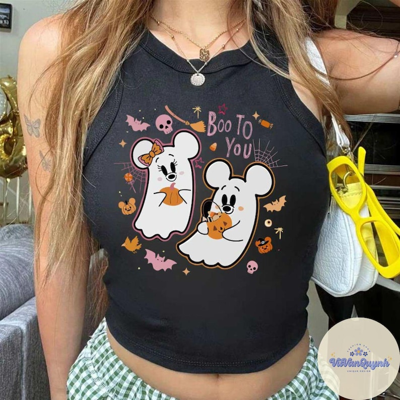 May include: Black crop top with a Halloween-themed graphic. The design features two ghost-like figures resembling cartoon mice, holding pumpkins, with the text "Boo To You". Bats, spiders, and other Halloween elements surround the figures.