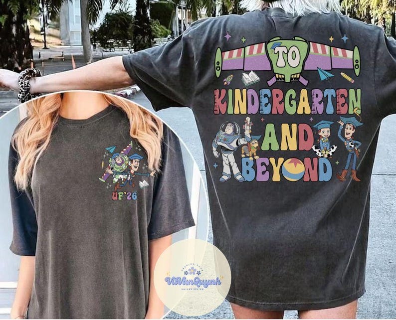 May include: Dark gray t-shirt with a colorful graphic featuring characters and the text "TO KINDERGARTEN AND BEYOND." The design includes Buzz Lightyear, Woody, and other characters. The front of the shirt has a smaller graphic and the letters "UF'26."