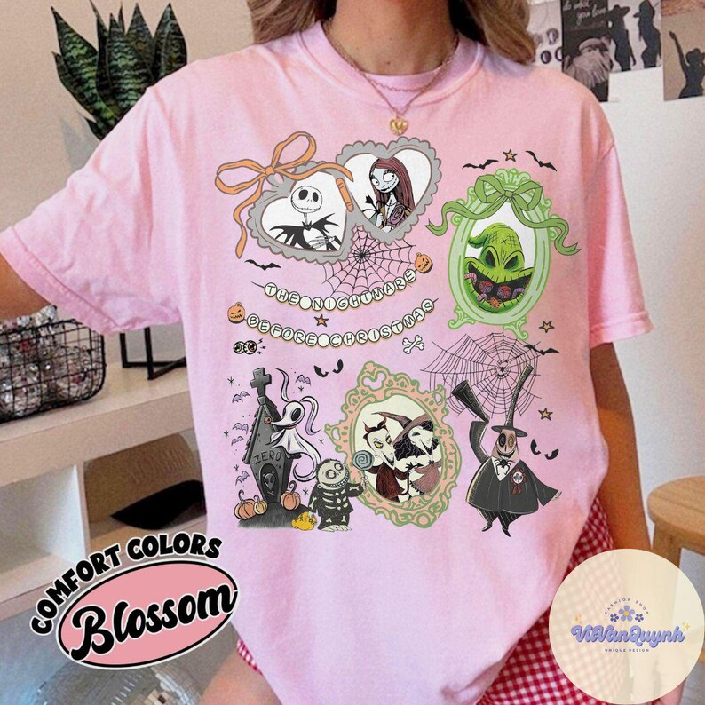 Puede incluir: Camiseta rosa claro con un dise&ntilde;o gr&aacute;fico que presenta personajes y elementos de "Pesadilla antes de Navidad". El dise&ntilde;o incluye retratos enmarcados, telara&ntilde;as y el texto "The Nightmare Before Christmas."