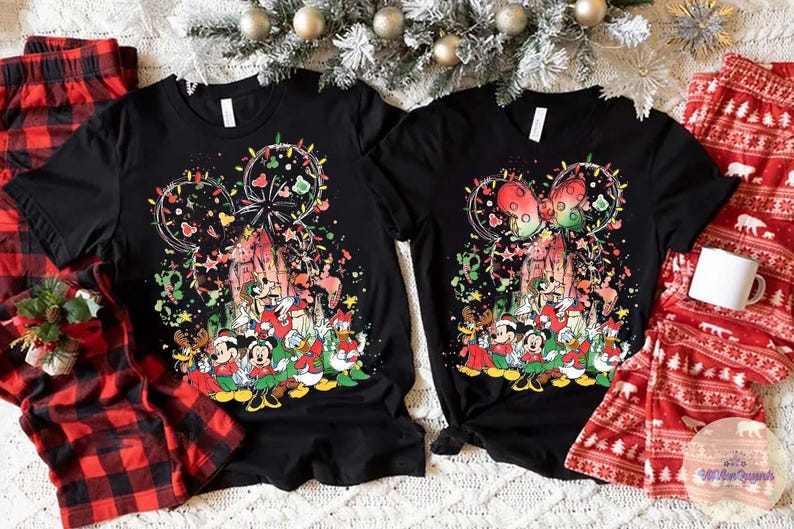 May include: Two black t-shirts with a colorful graphic featuring Mickey Mouse and friends in a Christmas theme. Red and black plaid pajama pants and red pajama pants with a white bear pattern are also visible.