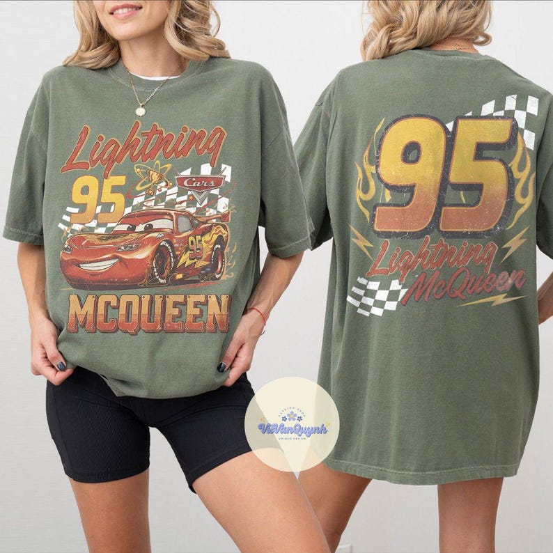 K&ouml;nnte beinhalten: Olivgr&uuml;nes Lightning McQueen T-Shirt mit einem verblassten Grafikdesign auf der Vorder- und R&uuml;ckseite. Die Vorderseite zeigt Lightning McQueen mit der Nummer 95, dem Text "Lightning McQueen" und "Cars". Die R&uuml;ckseite hat die Nummer 95 und "Lightning McQueen".
