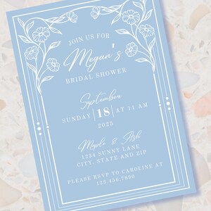 May include: A light blue bridal shower invitation with a white floral border. The invitation reads "Join us for Megan's Bridal Shower, Sunday, 18th September at 11 AM, 2025, Maple & Ash, 1234 Sunny Lane, City, State and Zip, Please RSVP to Caroline at 123.456.7890."