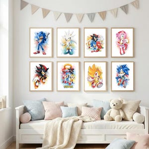 Könnte beinhalten: Eine Sammlung von acht gerahmten Kunstdrucken mit farbenfrohen Illustrationen von Sonic the Hedgehog-Charakteren. Die Kunstwerke zeigen Bilder von Sonic, Shadow und anderen Charakteren mit Aquarell-Hintergründen. Die Drucke werden über einem weißen Tagesbett mit Kissen ausgestellt.