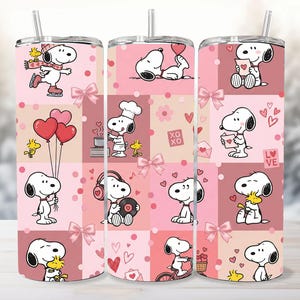 May include: A set of three stainless steel tumblers with a pink and white patchwork design featuring Snoopy and Woodstock in various Valentine's Day themed scenes. Each tumbler has a straw and a lid.