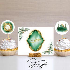May include: A festive Ramadan-themed display featuring cupcakes with white frosting and decorative toppers. The central element is a card with gold accents and Arabic calligraphy. The design includes floral elements and a cork base.