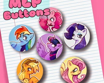 May include: Five circular pin-back buttons featuring colorful cartoon pony illustrations. The buttons display characters with pink, blue, purple, orange, and yellow color schemes. The text MLP Buttons is printed in pink bubble letters.