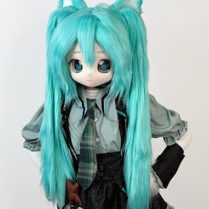 May include: A doll with a large head, blue eyes, and long, turquoise hair styled in pigtails. The doll wears a gray shirt, black vest, plaid tie, and a black skirt with ruffles. The doll has cat ears.
