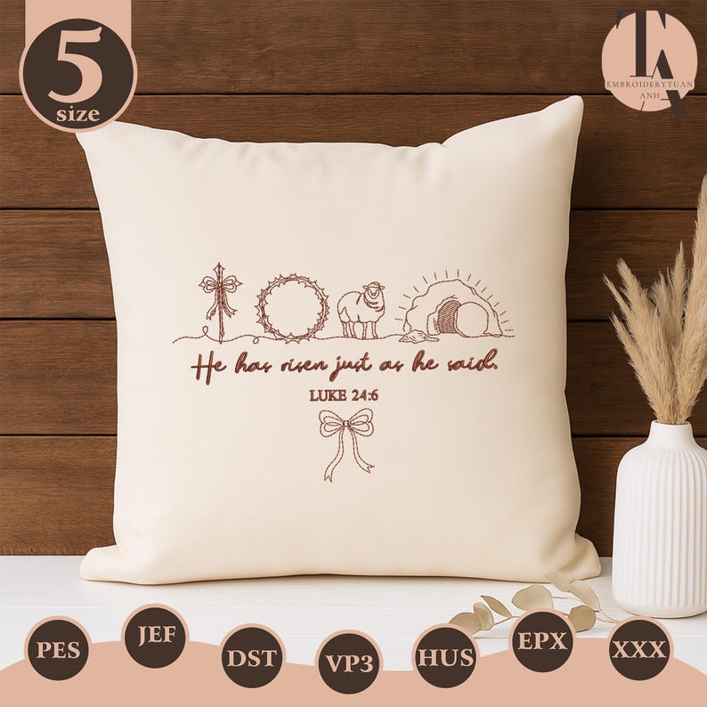 May include: Cream-colored decorative pillow with embroidered religious imagery. The design includes a cross, a crown of thorns, a lamb, and a tomb. The text "He has risen just as he said. Luke 24:6" is also embroidered on the pillow.