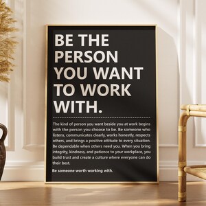 Puede incluir: Un póster rectangular negro con texto en blanco que dice: BE THE PERSON YOU WANT TO WORK WITH. Debajo, un párrafo con texto blanco más pequeño detalla la integridad en el trabajo, terminando con la frase: Be someone worth working with.