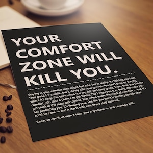 May include: A black poster with white text that reads "YOUR COMFORT ZONE WILL KILL YOU." The poster is on a wooden surface with coffee beans and a notebook. The text below explains the quote.