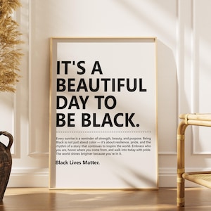 May include: A framed art print with the text "IT'S A BEAUTIFUL DAY TO BE BLACK." The print includes additional text about strength, beauty, and pride. A decorative vase with dried plants is on the left, and a bamboo bench is on the right.