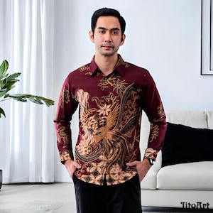 May include: A burgundy long-sleeve button-down shirt with a detailed gold and brown floral and bird pattern. The shirt has a classic collar and cuffs, and is worn with black pants. The shirt is made of a soft, comfortable material.