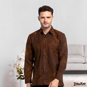 May include: A brown button-down shirt with a detailed, patterned design. The long-sleeved shirt features a collar and is made of a dark brown fabric with lighter brown accents. The shirt is worn by a person in a studio setting.