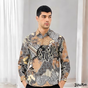 Op de afbeelding: Een overhemd met lange mouwen met een gedetailleerd batikpatroon in tinten bruin, zwart en crème. Het overhemd heeft een klassieke kraag en manchetten. Het ontwerp omvat bloemen en abstracte motieven, wat een unieke en artistieke uitstraling creëert.