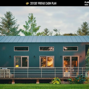 May include: A dark green prefab cabin plan measuring 26'x30' with a metal roof, horizontal siding, and a front deck featuring a metal railing. The structure includes three upper transom windows, two lower windows, and a glass door with light wood frames.
