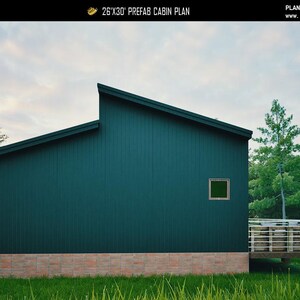 May include: A 26'x30' prefab cabin plan featuring dark teal vertical siding, a shed roof, a small square window, and a wooden deck with horizontal railings. The base of the structure is finished with light-colored brick masonry.