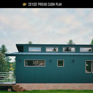 May include: A dark green prefab cabin with a metal roof, rectangular windows, and a wooden deck. The text reads 26'X30' PREFAB CABIN PLAN, PLAN C-25-109, and homeplandiy.com. The structure features a brick-patterned base and exterior wall lights.