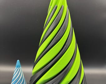 May include: Two decorative cone-shaped objects. The larger cone is green and black, with a spiral design. The smaller cone is blue and white, also with a spiral design. Both objects are on a black surface.