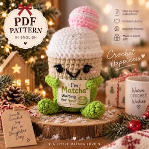 Pode incluir: Um padrão de crochê em PDF em inglês apresentando um personagem de bebida matcha de pelúcia com cobertura branca, um pompom rosa e corpo verde. O personagem segura uma placa com os dizeres I'm Matcha Waiting for You! e uma xícara.