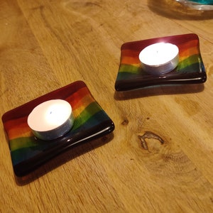 Könnte beinhalten: Zwei regenbogenfarbene Kerzenhalter aus Glas mit türkisfarbenen Akzenten. Jeder Halter hat eine kleine weiße Teelichtkerze.