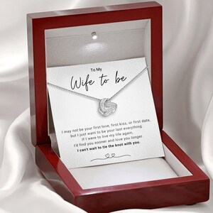 May include: A red velvet box with a white card inside that reads "To My Wife to be". The card has a silver knot necklace with a message about love and marriage.