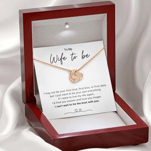 May include: A red wooden box with a white card inside. The card has a gold necklace with a knot design and the text "To My Wife to be" and a message about love and marriage.