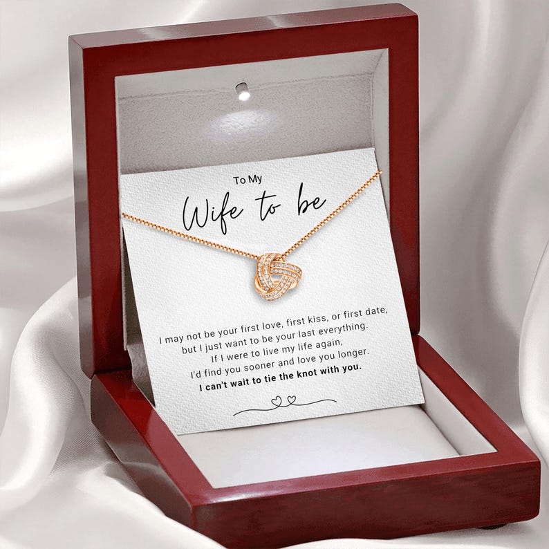 May include: A red wooden box with a white card inside. The card has a gold necklace with a knot design and the text "To My Wife to be" and a message about love and marriage.